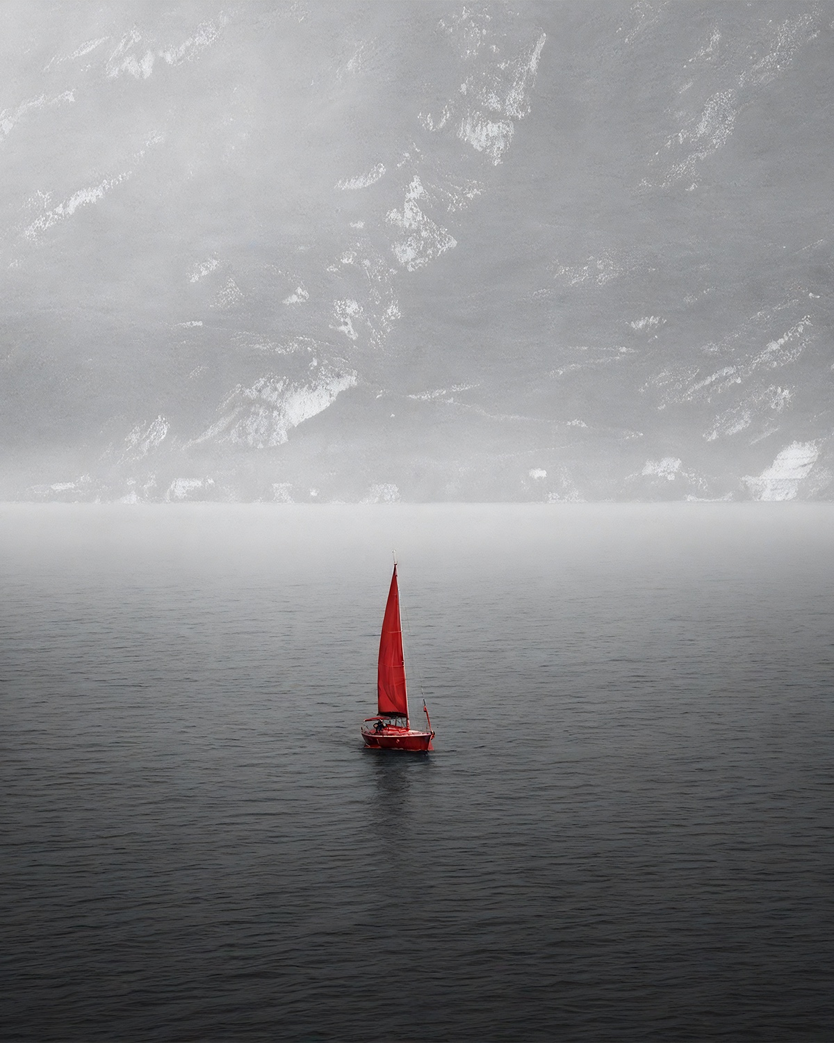 Small red sailboat inside a large silver seascape